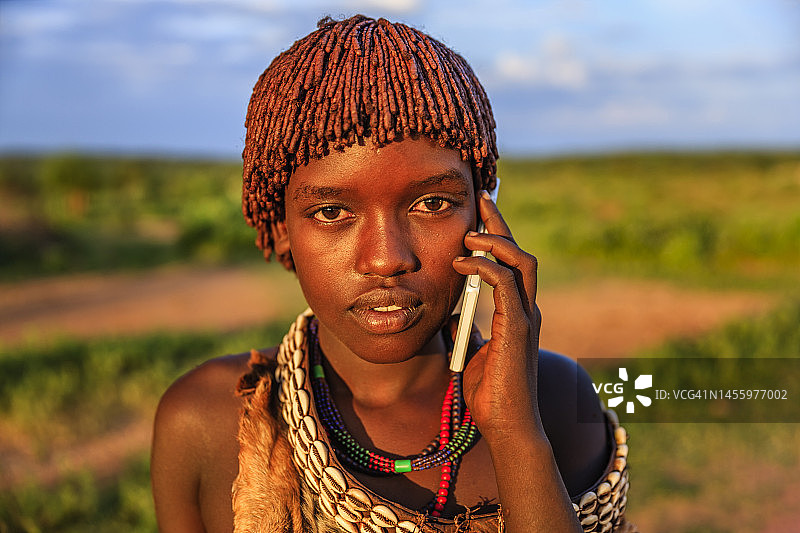 来自哈默的年轻女子在非洲埃塞俄比亚奥莫山谷使用智能手机图片素材