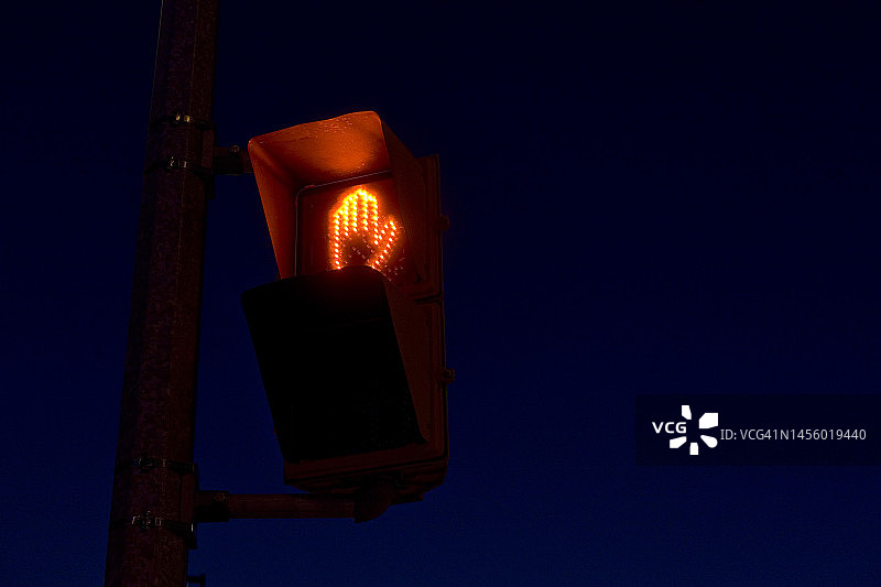 道路交叉口点亮的橙色“禁止通行”手势标志图片素材