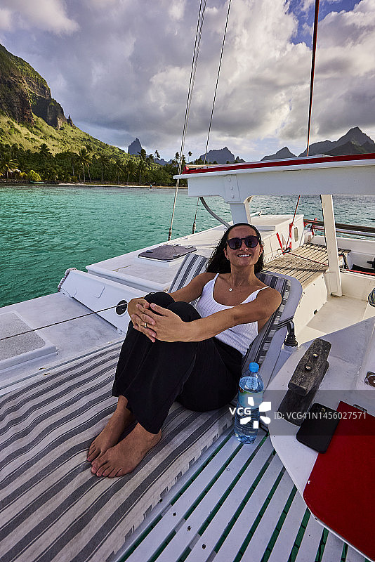 年轻女人在双体船甲板上放松图片素材