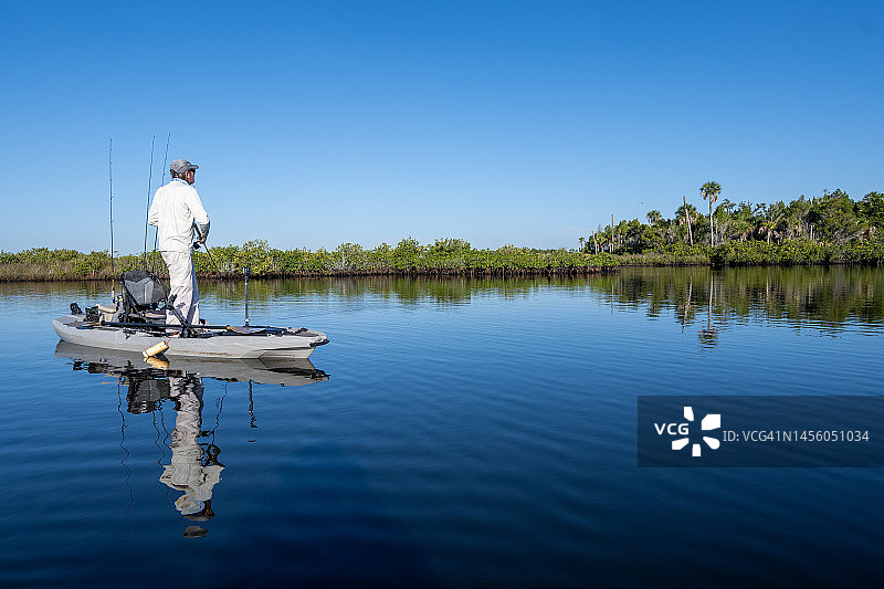 在平静水面上钓鱼的皮划艇爱好者图片素材