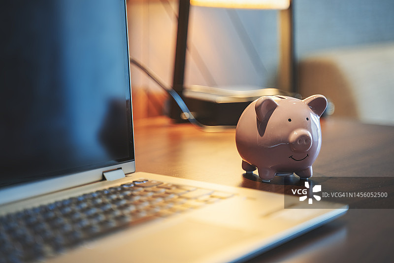 办公桌上的储蓄罐和笔记本电脑图片素材
