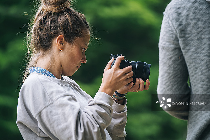 年轻女子在户外使用数码相机图片素材