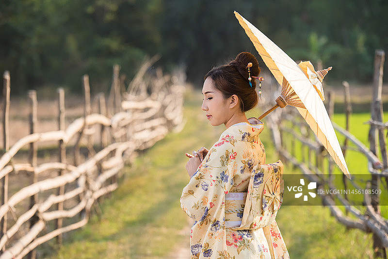 身穿文化服饰的日本女孩，背对着镜头，手持雨伞图片素材