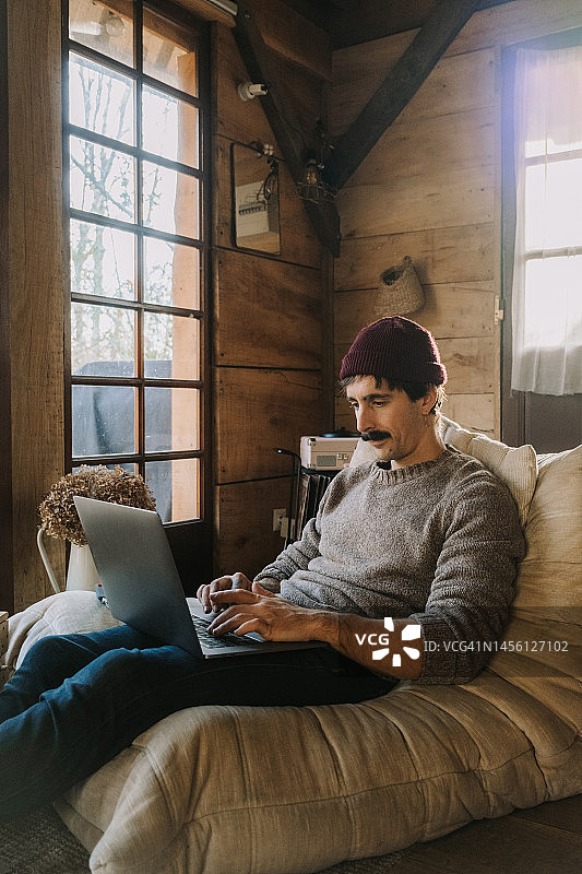 在木屋里使用笔记本电脑的成年男子图片素材