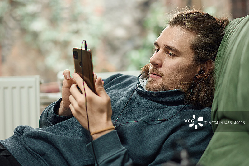 年轻男人戴着耳机看手机图片素材