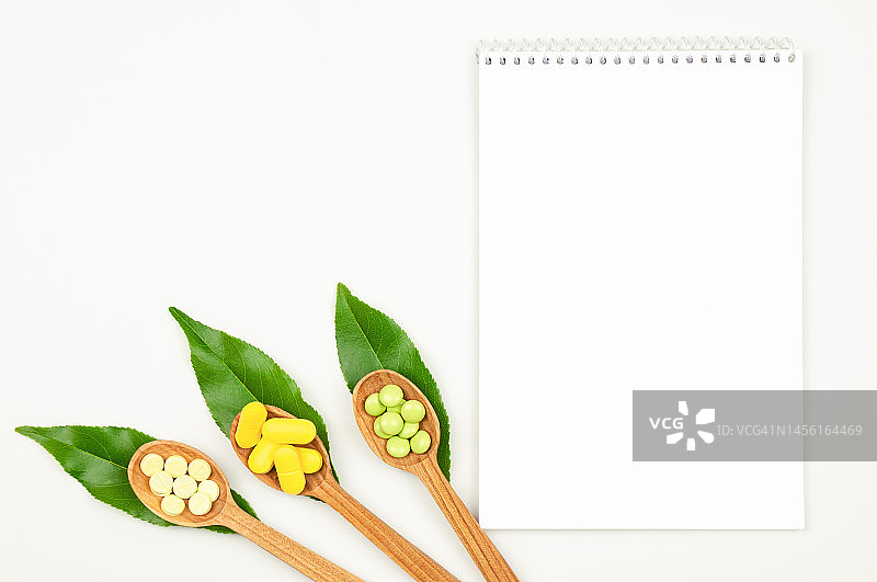 白色背景上的空白记事本、木勺与草药药丸图片素材