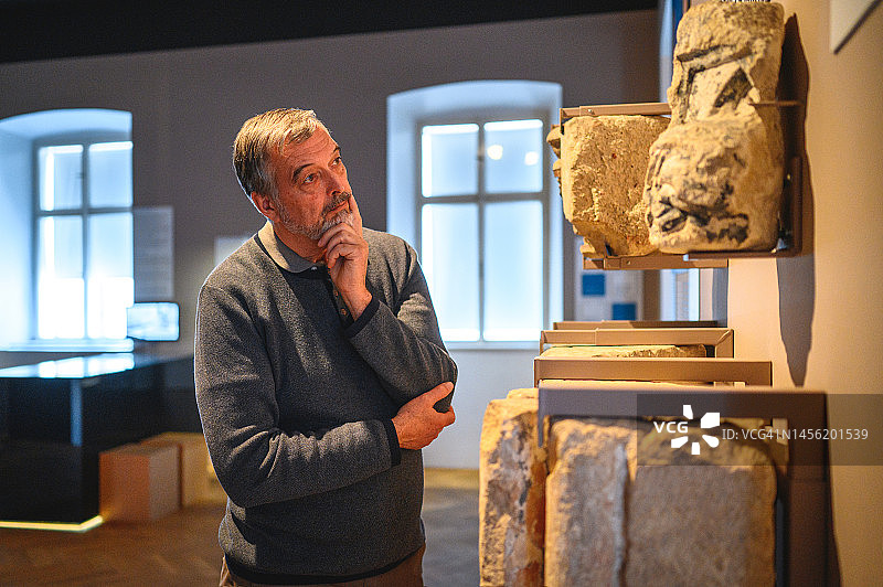 欣赏古老墓碑的灰发男人图片素材