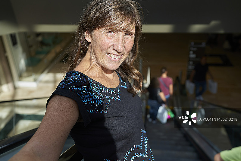 站在滚梯上自拍的微笑女人，高角度视角图片素材