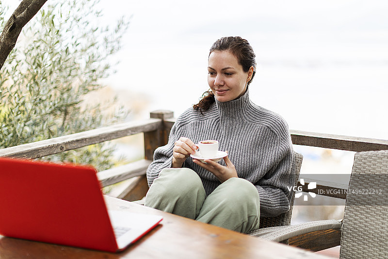 女人在乡间别墅远程办公，手捧一杯咖啡图片素材