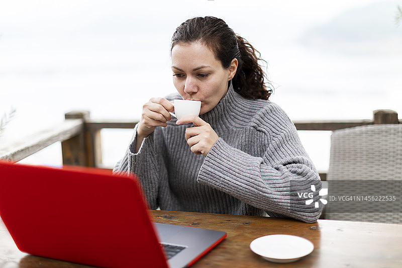 女人在乡间别墅远程办公，手捧一杯咖啡图片素材