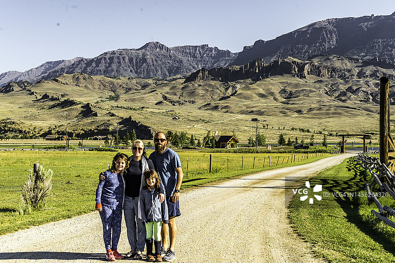 怀俄明州乡村背景下，妈妈、爸爸和女儿们微笑的可爱全家福图片素材
