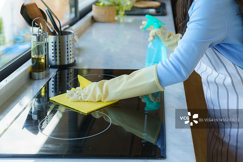 亚洲家庭主妇在厨房用抹布擦拭电炉图片素材