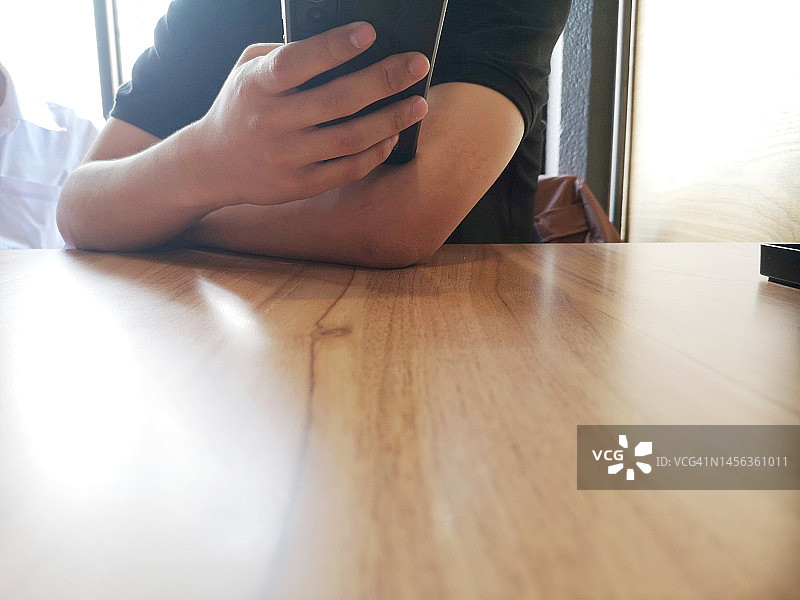 男孩在桌旁用手机拍照图片素材