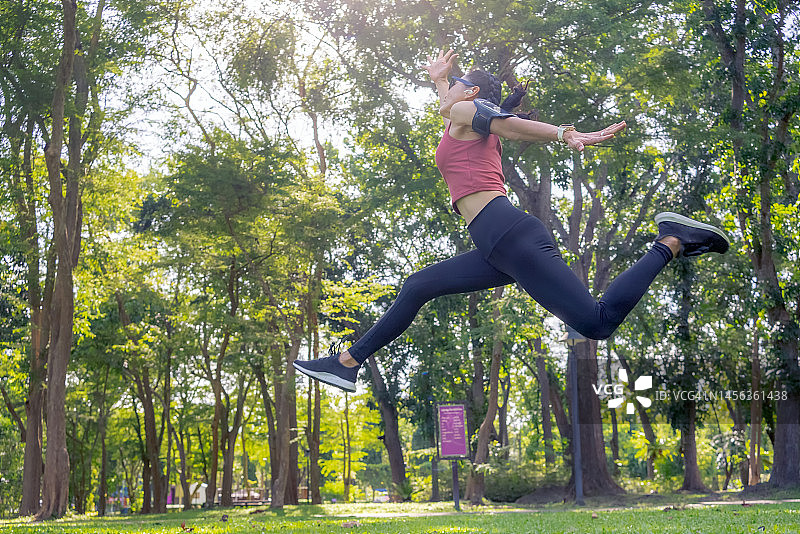亚洲女人在公园跑步和跳跃图片素材