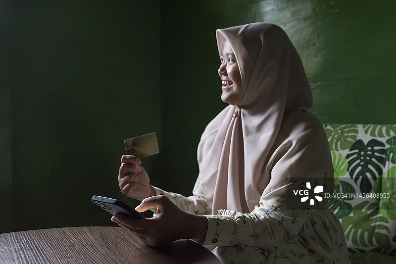 穆斯林妇女在家通过智能手机在网上购物图片素材