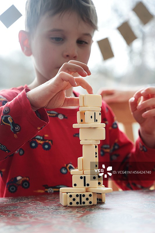 男孩在桌子上堆放多米诺骨牌图片素材