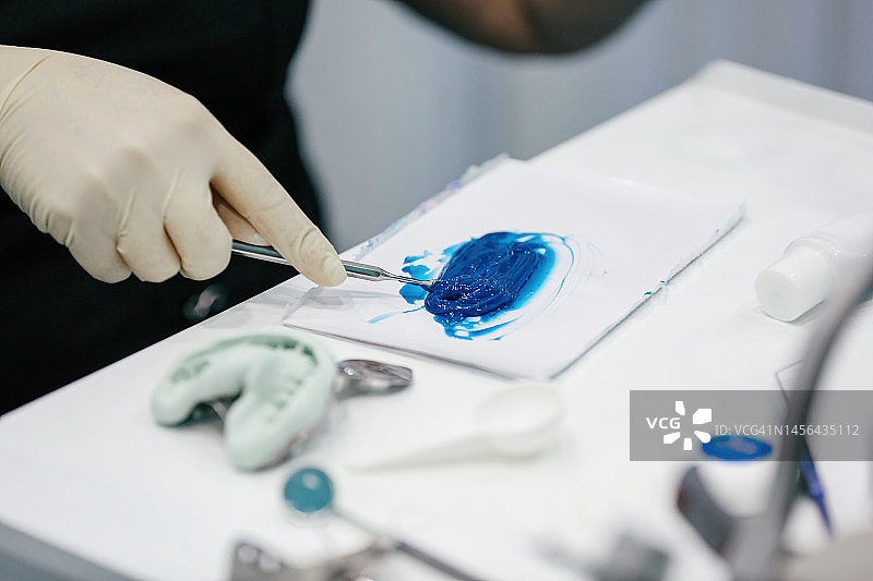 正畸医生在牙科实验室工作并混合蓝色牙科粘合剂图片素材