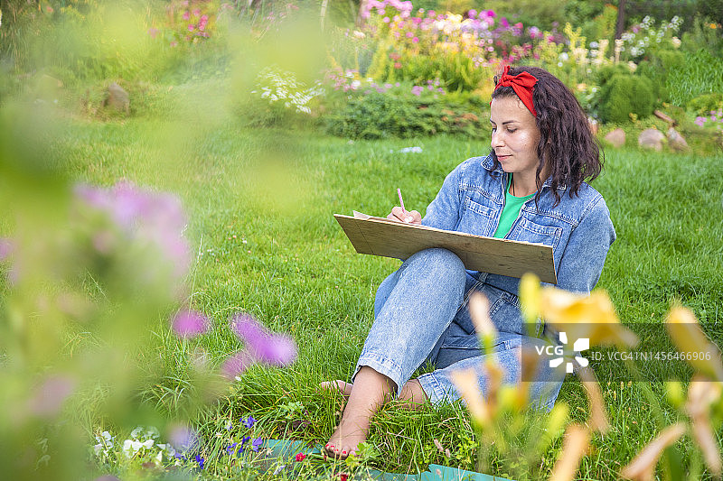 女人在户外写生垫上画花图片素材