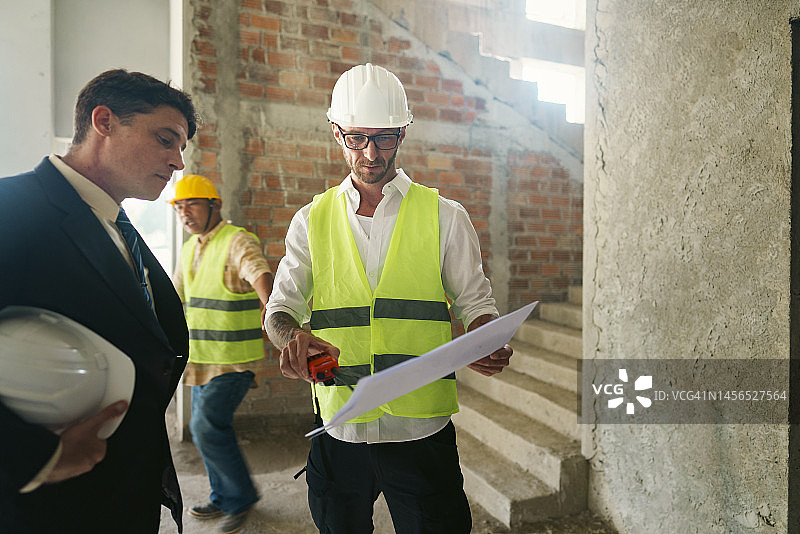 成年业主检查建筑材料并与工程师解决施工现场问题图片素材