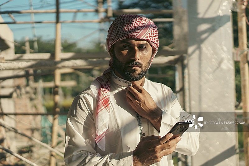 身着传统服饰的阿拉伯投资者用手机查看施工现场图片素材