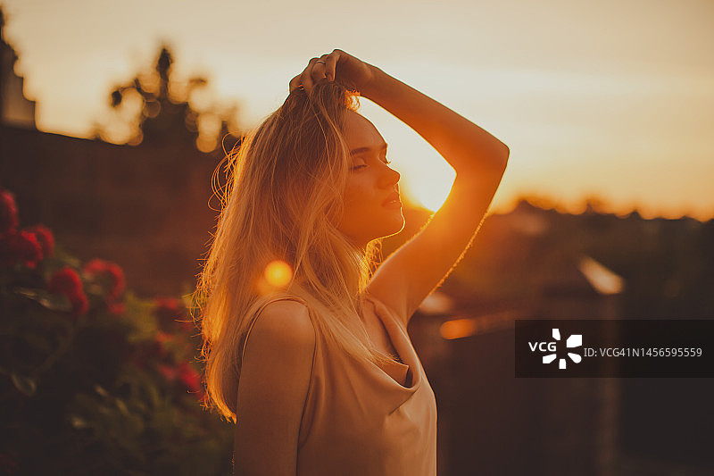 夕阳下的金发女子与玫瑰花园图片素材