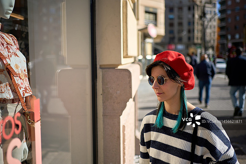 在精品店橱窗购物的年轻女人图片素材