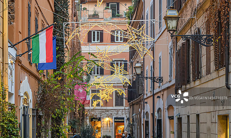 圣诞假期期间的玛古塔大街，装饰着圣诞灯饰。历史建筑上的意大利和欧盟旗帜，意大利罗马图片素材