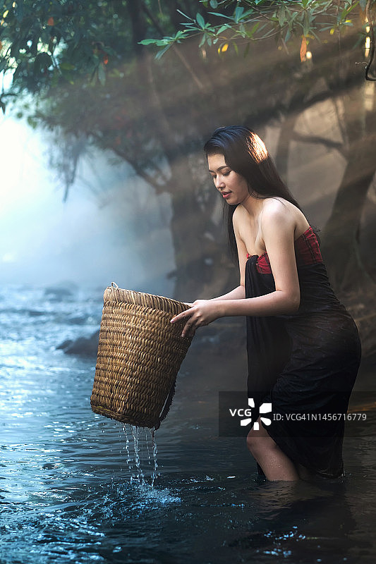 在小溪里工作的亚洲妇女：以传统方式洗衣图片素材
