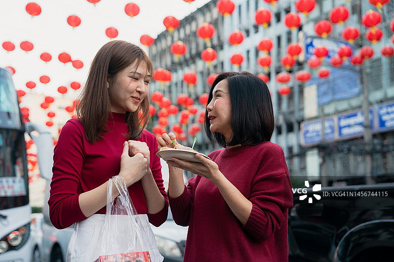 中国新年，亚洲母亲和女儿在唐人街旅行和吃街头小吃图片素材