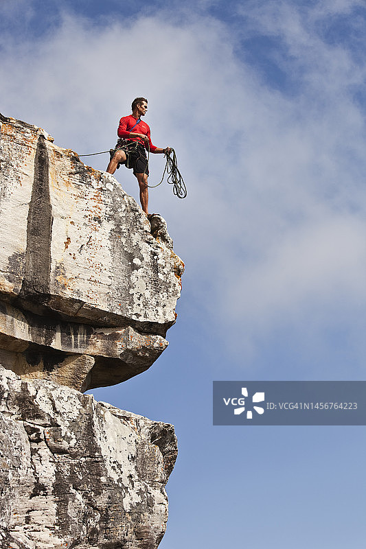 男性攀岩者准备用绳索从悬崖峭壁上垂降图片素材