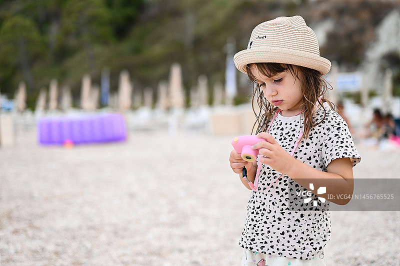 孩子在沙滩用儿童相机玩耍图片素材