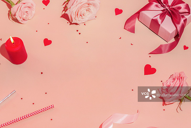 情人节框架构图与复制空间：白色礼品盒与品红色蝴蝶结，红色心形五彩纸屑，玫瑰，红色蜡烛和迪斯科球在柔和的背景。顶视图，平躺，假日概念图片素材