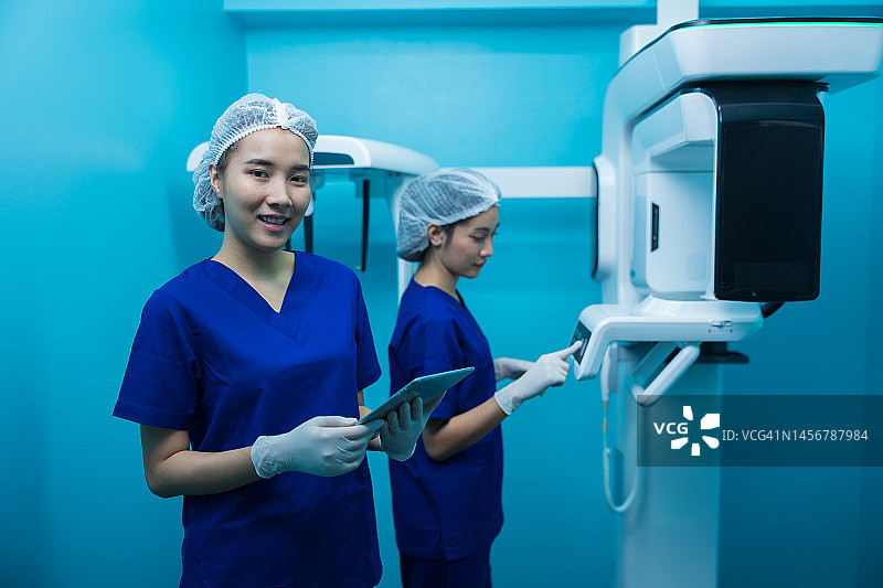 两名亚洲女性使用平板电脑讨论牙科X光机图片素材