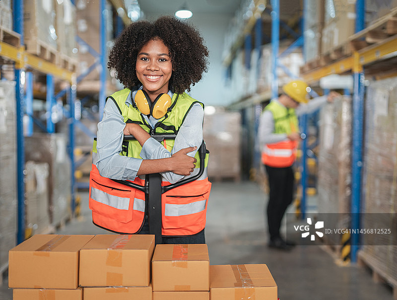 仓库配送中心微笑的非洲裔女工和叉车肖像图片素材