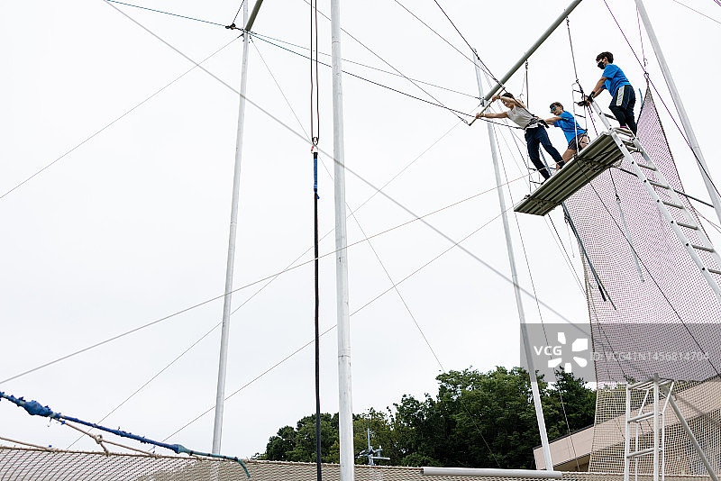 年轻女子准备从高空秋千跳板上跳下图片素材
