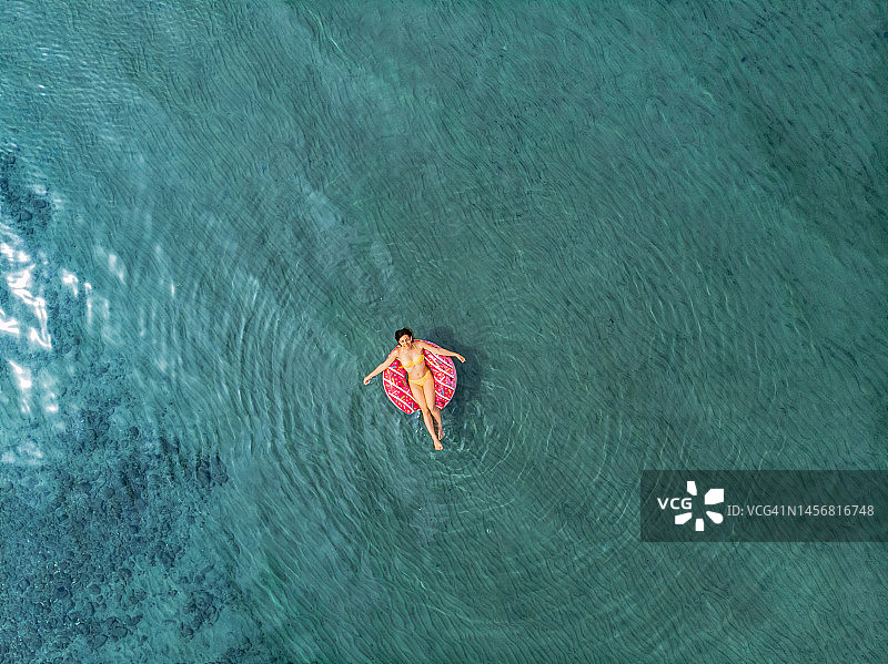 年轻女人在充气泳池玩具上漂浮在海中图片素材