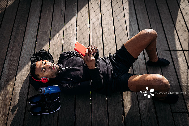 戴着耳机在码头上放松的年轻男子图片素材