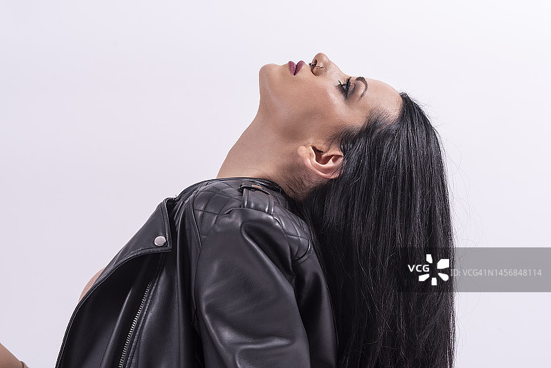 三十多岁的年轻女子在影棚拍摄时尚写真，白色背景，身穿皮夹克，柔顺长发特写图片素材