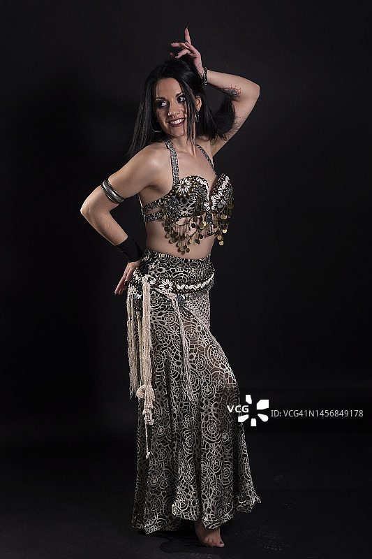 三十多岁的年轻女子在演播室摆姿势，黑色背景上的时尚照片，佩戴时尚配饰，跳阿拉伯舞七层面纱图片素材