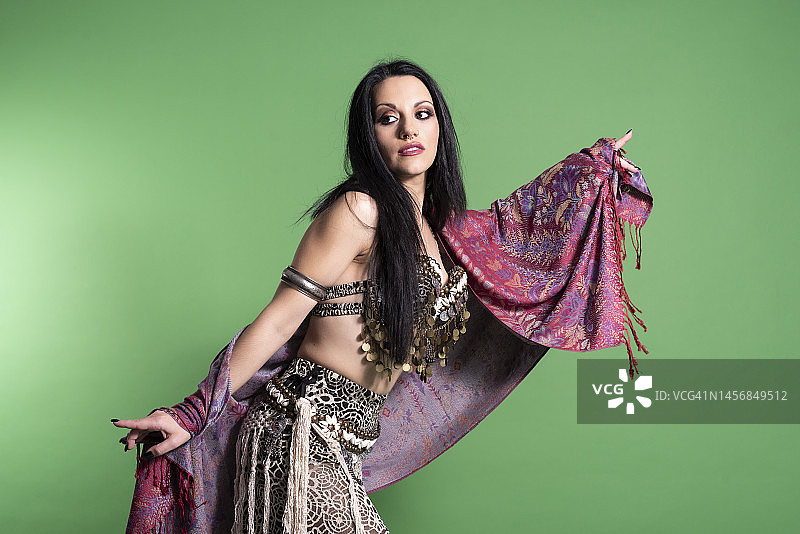 三十多岁的年轻女子身着阿拉伯服装在绿色背景上拍摄时尚照片图片素材