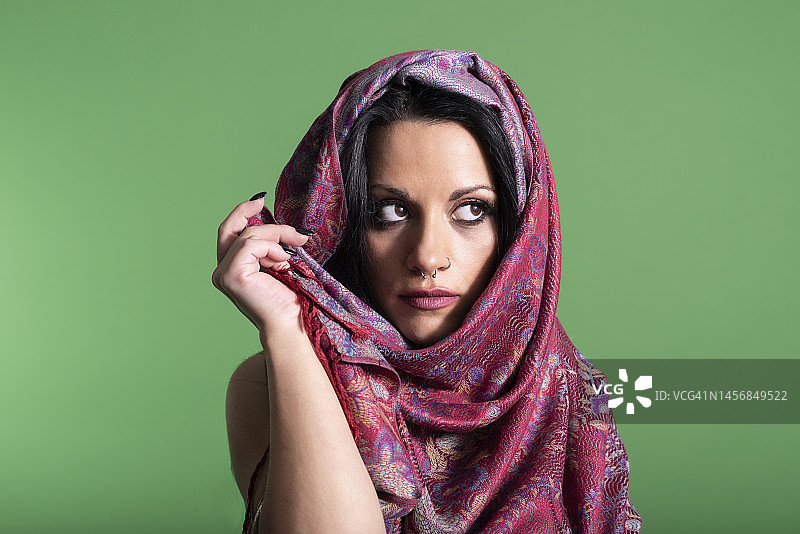 三十多岁的年轻女子身着阿拉伯服装在绿色背景上拍摄时尚照片图片素材