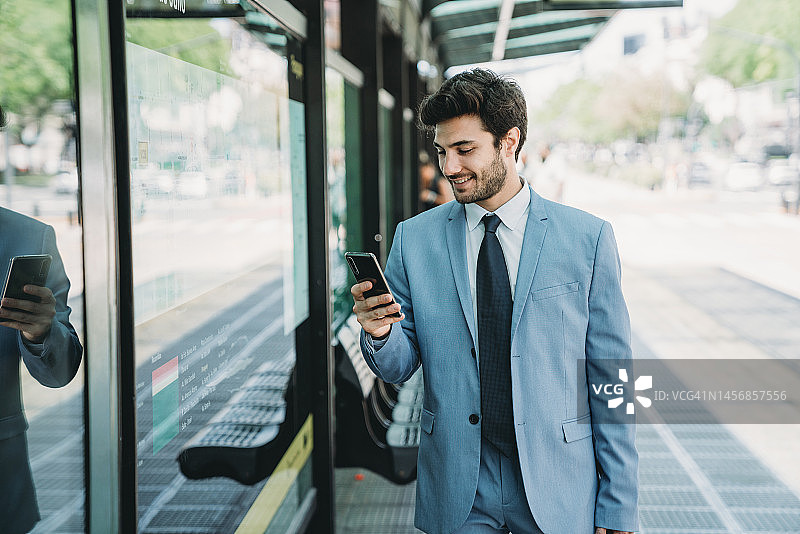 在公交车站用智能手机查看地图的年轻男商人图片素材