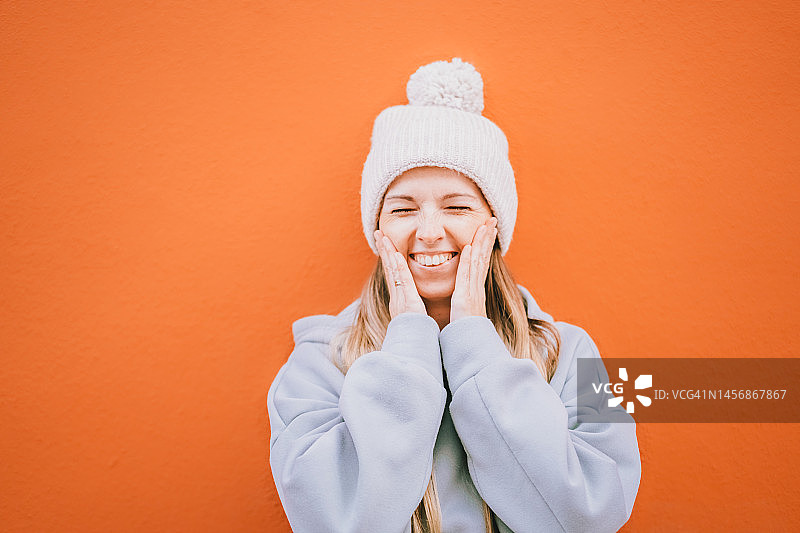 在橙色背景下欢笑的美丽快乐的欧洲女人图片素材