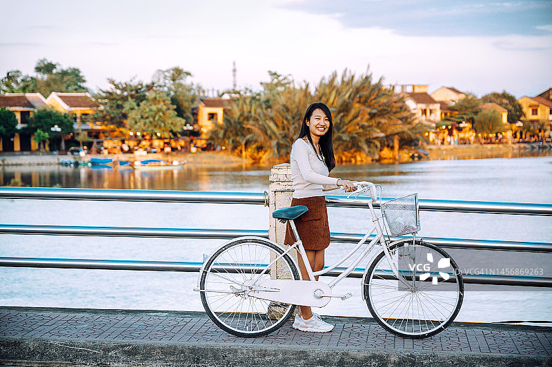快乐的越南女人骑自行车过桥图片素材