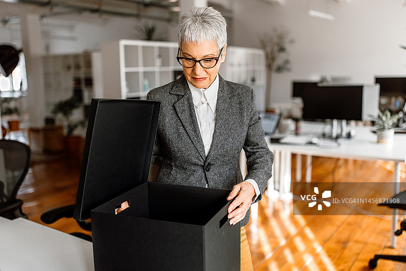 中年妇女在办公室里拿着装有个人物品的盒子图片素材