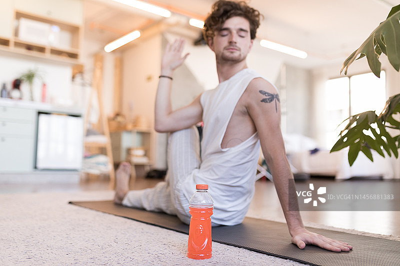 男人在做瑜伽，旁边放着等渗饮料图片素材