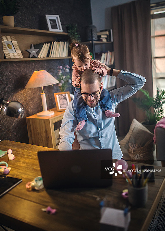 父亲在家工作，同时照顾他的女婴图片素材