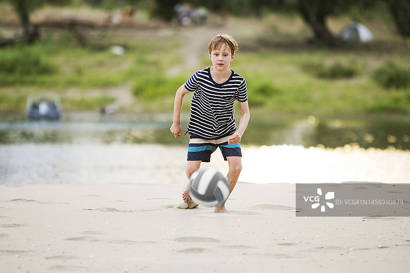 小男孩在海滩踢足球图片素材