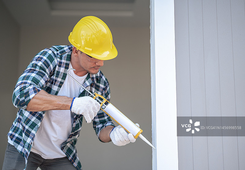 男建筑工人在建筑工地使用硅酮密封胶图片素材