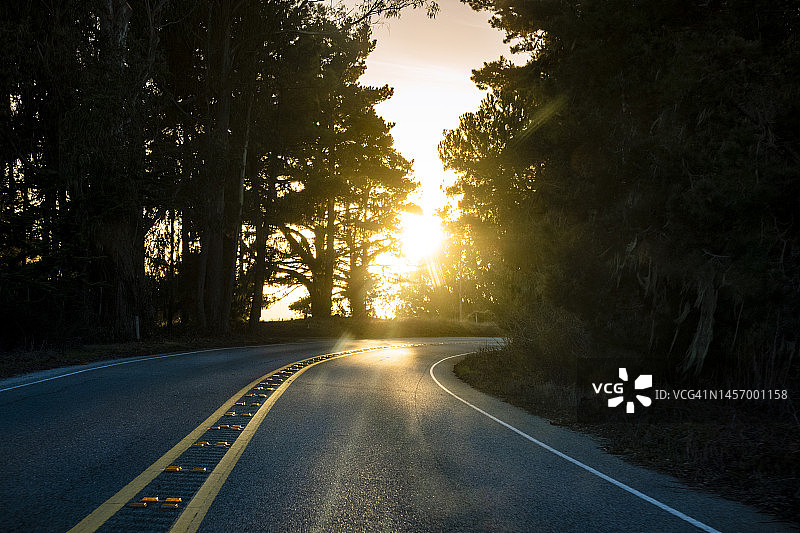 在日落时分行驶在弯曲的道路上图片素材
